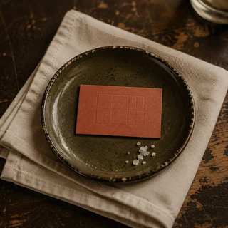 Plato de cerámica, servilleta de lino y tarjeta con relieve geométrico.